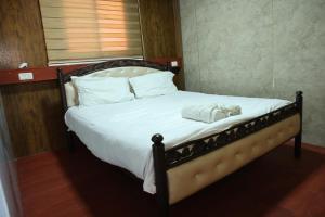 a bed with white sheets and a towel on it at נוף הכפר - 6 חדרי אירוח לזוגות ומשפחות עם ג'קוזי ובריכה מחוממת משותפים במתחם in Buq‘ātā