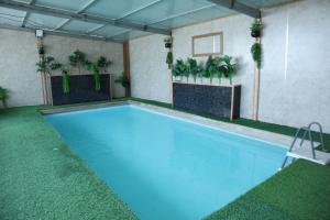 a indoor swimming pool with blue water and plants at נוף הכפר - 6 חדרי אירוח לזוגות ומשפחות עם ג'קוזי ובריכה מחוממת משותפים במתחם in Buq‘ātā