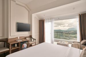 a hotel room with a bed and a large window at Hill Side Town Hotel DaLat in Da Lat