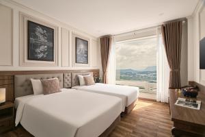 two beds in a hotel room with a window at Hill Side Town Hotel DaLat in Da Lat
