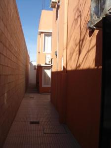 Nec Apart Hotel في Las Perdices: طريق زقاق مع مبنى وجدار من الطوب