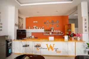 a kitchen with a counter with an orange wall at Hotel Pratisarawirya by The Loka in Surabaya