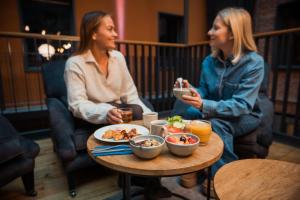 two women sitting at a table eating food at Clarion Hotel Mestari in Helsinki