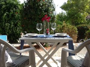 un tavolo bianco con due sedie e due bicchieri da vino di Pissouri Beach House - Image a Pissouri