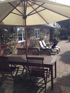 - une table en bois avec un parasol sur la terrasse dans l'établissement Country B&B Horsens, à Horsens