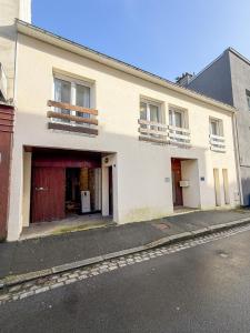 a white building with two doors and a balcony at L'Escale St Nicolas in Hennebont