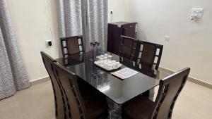 a dining room table with four chairs and a black table at Elite Villa Raipur - Luxury Homestay in Raipur