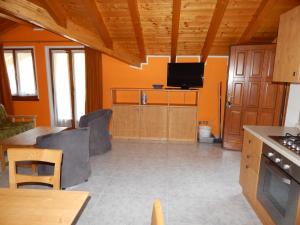 een keuken met oranje muren en een tafel en een tv bij Residence Vittoria in Pinzolo