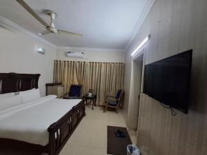 a bedroom with a bed and a flat screen tv at ButtLodges - 1 in Islamabad