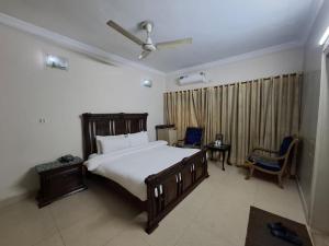 a bedroom with a large white bed and a window at ButtLodges - 1 in Islamabad