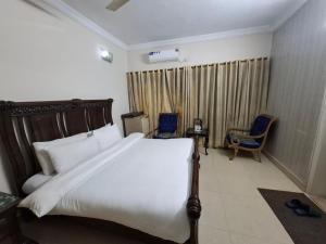 a bedroom with a large white bed and a chair at ButtLodges - 1 in Islamabad +16 photos