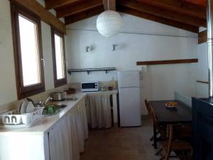 cocina con nevera blanca y mesa en Casa Rural El Aljibe, en Benamahoma