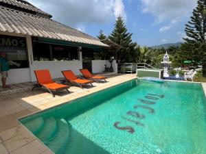 a swimming pool with orange chairs next to a building at TopCats Fishing Resort in Taling Ngam Beach