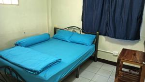 a room with two beds with blue pillows and a table at เจแปน บ้านพักรายวัน in Pak Chong