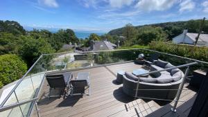 a deck with a couch and chairs on a balcony at Woodcroft in Pwllheli