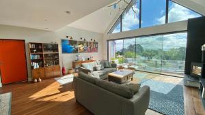 a living room with a couch and a large window at Woodcroft in Pwllheli
