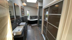 a bathroom with two sinks and a bath tub at Woodcroft in Pwllheli +21 photos