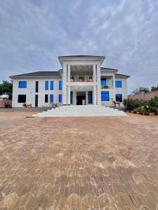 a large white building with blue windows and a patio at Mbogo Safari Hotel in Karatu