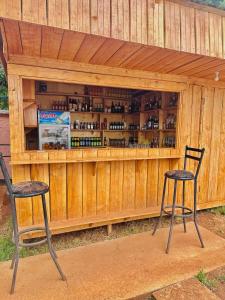 two chairs in front of a wooden bar with wine bottles at Mbogo Safari Hotel in Karatu
