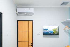 a room with a door and a tv on the wall at Behomy Suhat Malang in Karangjepun