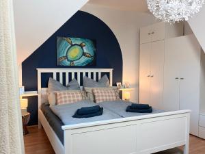 a bedroom with a white bed with a blue accent wall at Stilvolle, ruhige Wald-FeWo - Kaminofen, Dachterrasse, hundefreundlich in Remscheid