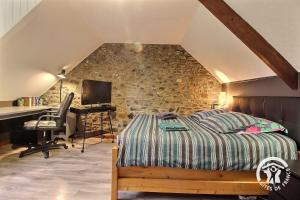 a bedroom with a bed and a desk with a computer at Le bois du chat in Plouha