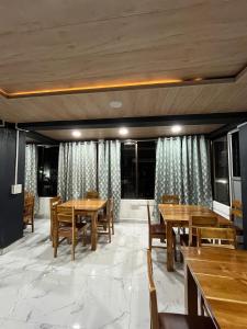 a dining room with wooden tables and chairs at Aizawl View Hotel in Āīzawl +1 photo