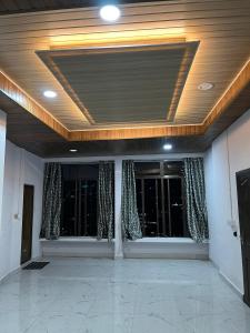 an empty room with two windows with curtains at Aizawl View Hotel in Āīzawl