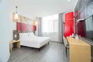 a hotel room with a white bed and a tv at Ibis Shanghai Xujiahui in Shanghai +31 photos