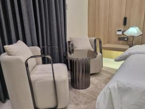 a room with two chairs and a table and a bed at Hotel Signature Gwangju in Gwangju +3 photos