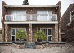 a brick building with two palm trees in front of it at Twin Okes in Jeffreys Bay