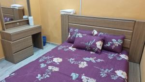 a bedroom with a bed with purple sheets and purple pillows at SriStar in Kluang