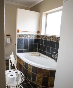 a bathroom with a bath tub and a window at Twin Okes in Jeffreys Bay