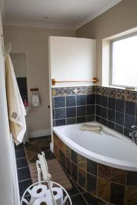 a bathroom with a large tub and a window at Twin Okes in Jeffreys Bay