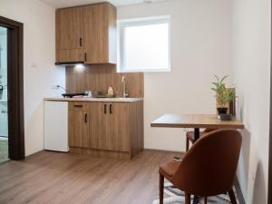a kitchen with wooden cabinets and a table with chairs at Megdan prenočište in Požarevac