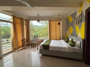a bedroom with a bed and a large window at Hotel Clover Inn malsi in Dehradun