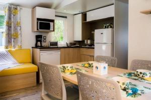 a kitchen with a table and chairs in a kitchen at ZEcamping 4 étoiles familial espace aquatique locatif TV LV clim in Sérignan
