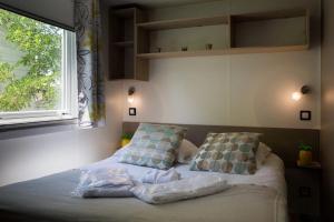a bedroom with a bed with two pillows and a window at ZEcamping 4 étoiles familial espace aquatique locatif TV LV clim in Sérignan
