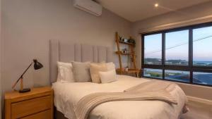 a bedroom with a bed and a large window at Blue Bay Studio Apartment in Wilderness