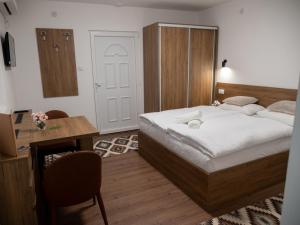 a bedroom with a bed and a desk and a chair at Megdan prenočište in Požarevac +19 photos