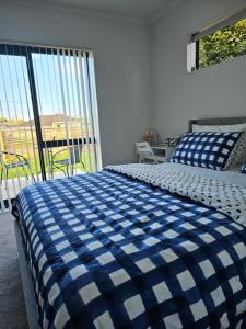 a bedroom with a blue and white bed and a balcony at Hillcrest Home in Hamilton