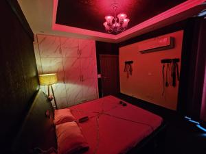 a red room with a bed and a lamp at The Secret Escape in Bahādurgarh