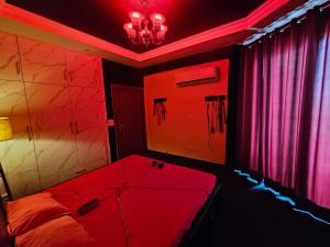 a red room with a bed and a chandelier at The Secret Escape in Bahādurgarh