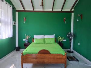 a green bedroom with a bed with a green wall at Fair view in Induruwa