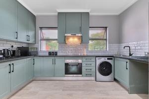 a kitchen with green cabinets and a washer and dryer at Afrikaya Luxurious Apartment in Roodepoort