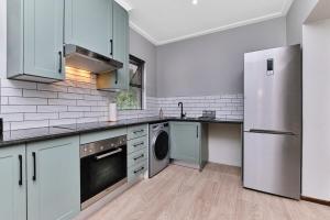 a kitchen with blue cabinets and a stainless steel refrigerator at Afrikaya Luxurious Apartment in Roodepoort +18 photos