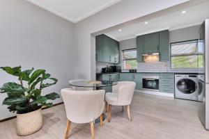 a kitchen with green cabinets and a table and chairs at Afrikaya Luxurious Apartment in Roodepoort