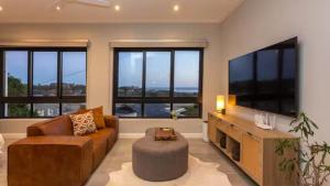 a living room with a couch and a tv and windows at Blue Bay Studio Apartment in Wilderness