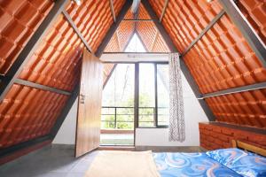 a room with a bed and a large window at teak trail in Pune
