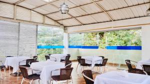 a room with white tables and chairs and windows at Hotel Cristal Plaza in Popayan